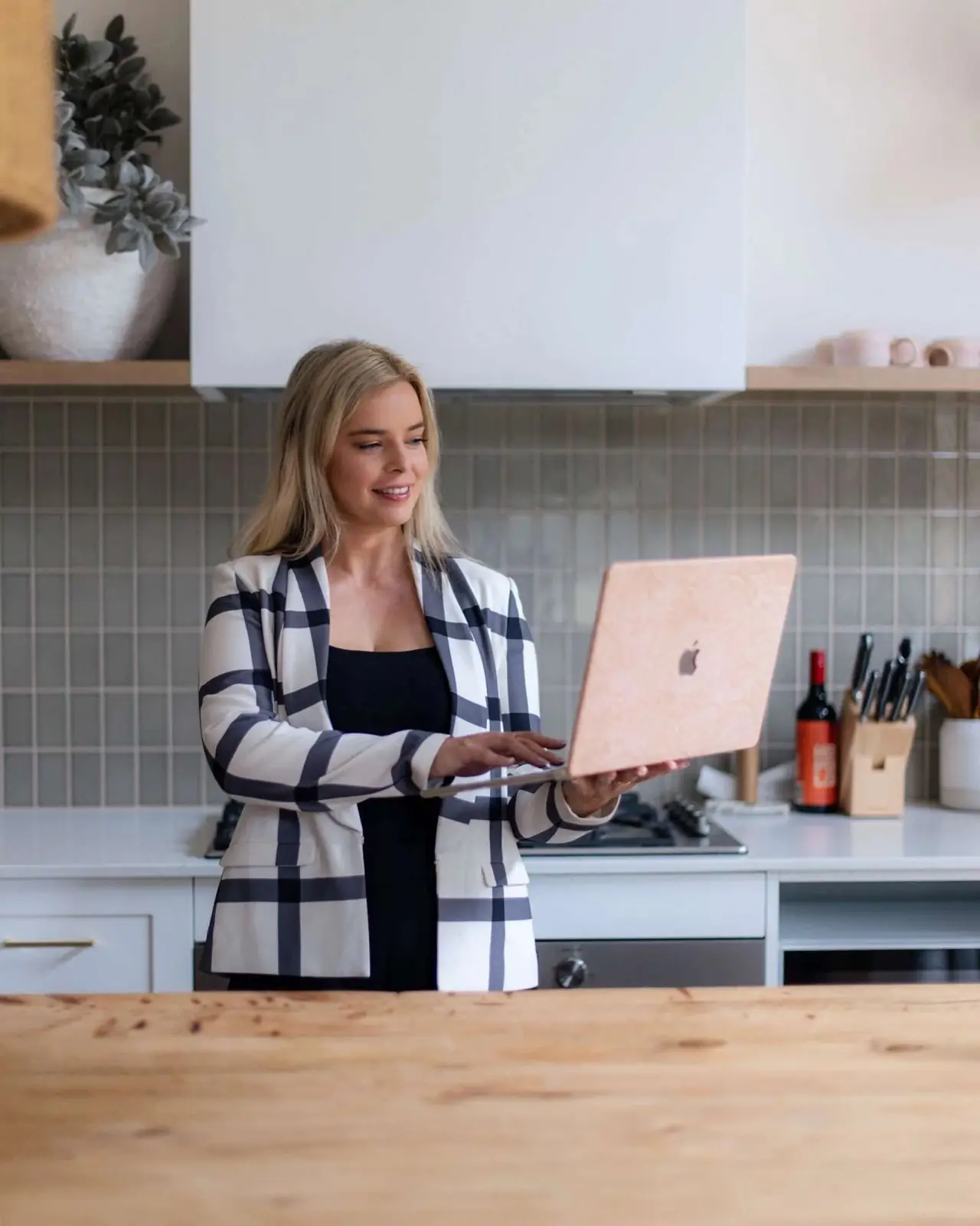 Charlotte from Comfy Creative working on her laptop in a bright kitchen
