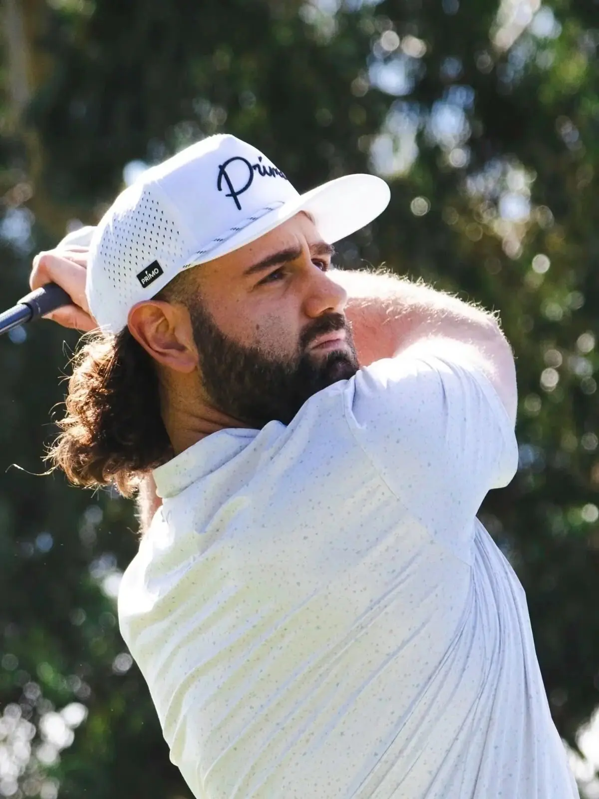 A golfer mid swing wearing a Tee Game cap